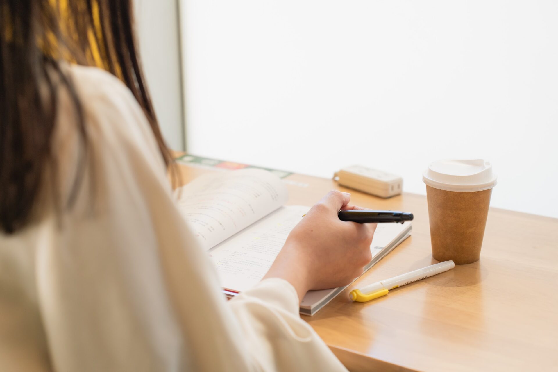 仕事帰りにカフェでノートを開いて国家資格の勉強をする社会人